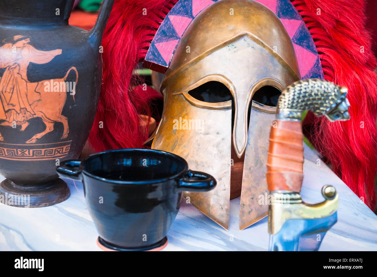 Spartan still-life di una spada, un casco militare, un bicchiere di vino e un anfora su un tavolo Foto Stock