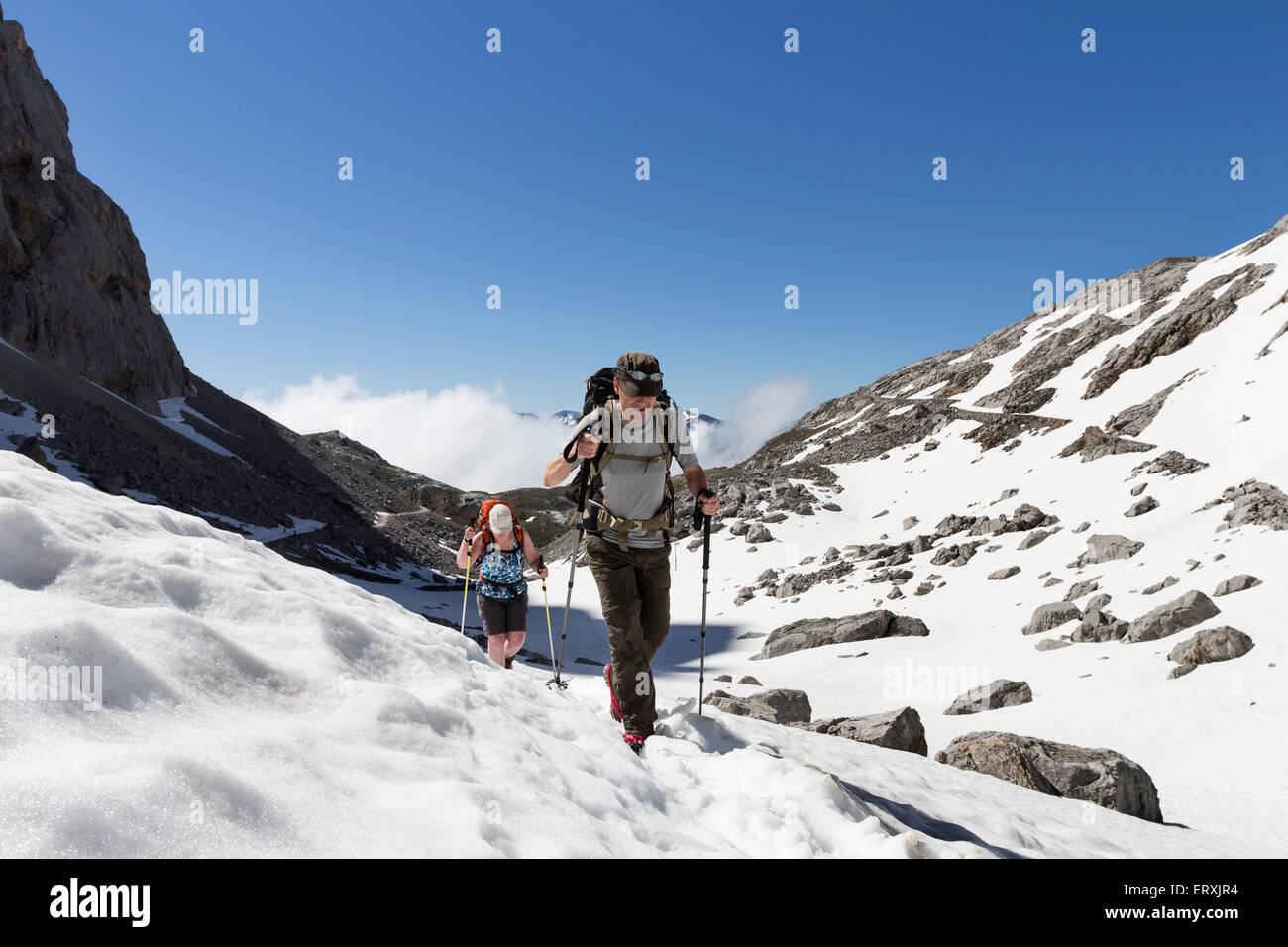 Gli escursionisti attraversa neve di primavera sui campi del La Vueltona (PR 23) Percorso Picos de Europa Cordillera Cantabria Spagna Foto Stock