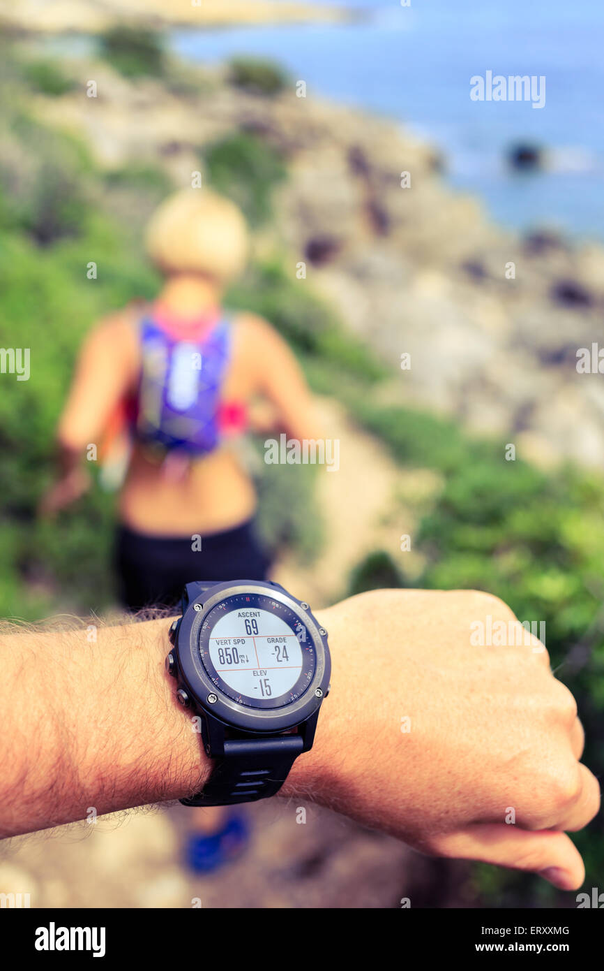 Runner o escursionista sul sentiero di montagna guardando orologio sportivo, uno stile di vita sano. Controllo posizione GPS, le prestazioni o la frequenza cardiaca p Foto Stock