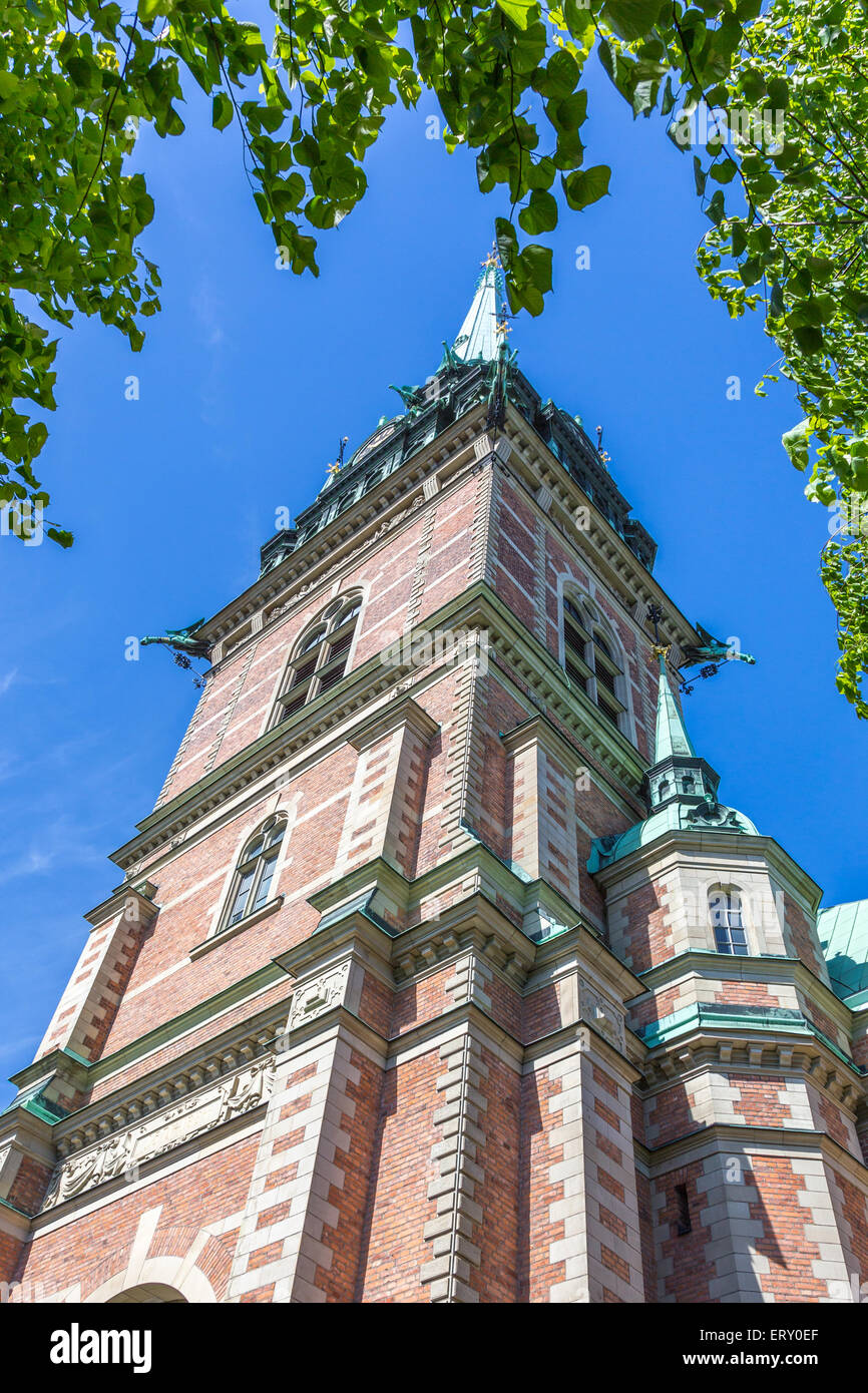 Vecchia chiesa (Tyska Kyrkan) In Gamla Stan, Stoccolma, in piedi contro il cielo azzurro incorniciato da un ampio e verde Leafcover Foto Stock