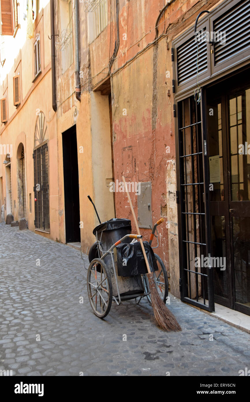Un pulitore di via dell'equipaggiamento su una stretta strada laterale in Sant'Angelo, in un quartiere di Roma, Italia. Foto Stock