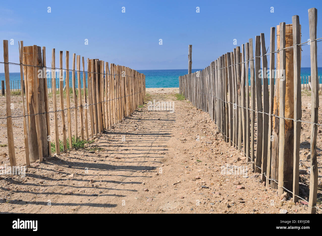 Percorso in sabbia che portano al mare delimitato da recinzione di legno Foto Stock