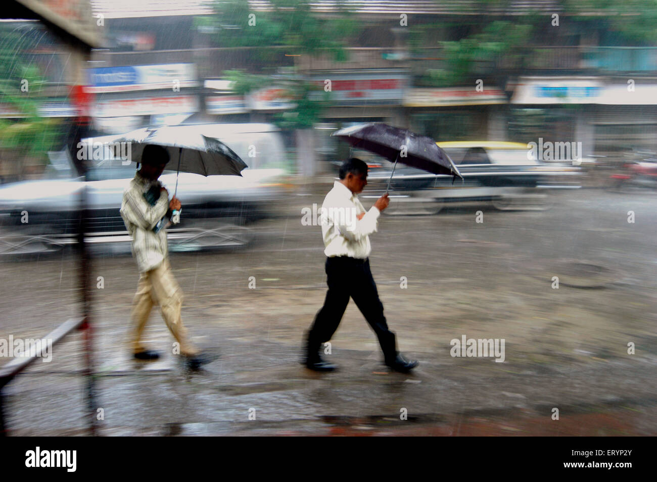 Pendolari di proteggere se stessi con i propri ombrelli come essi a piedi in pesanti piogge durante la stagione dei monsoni a Bombay Foto Stock