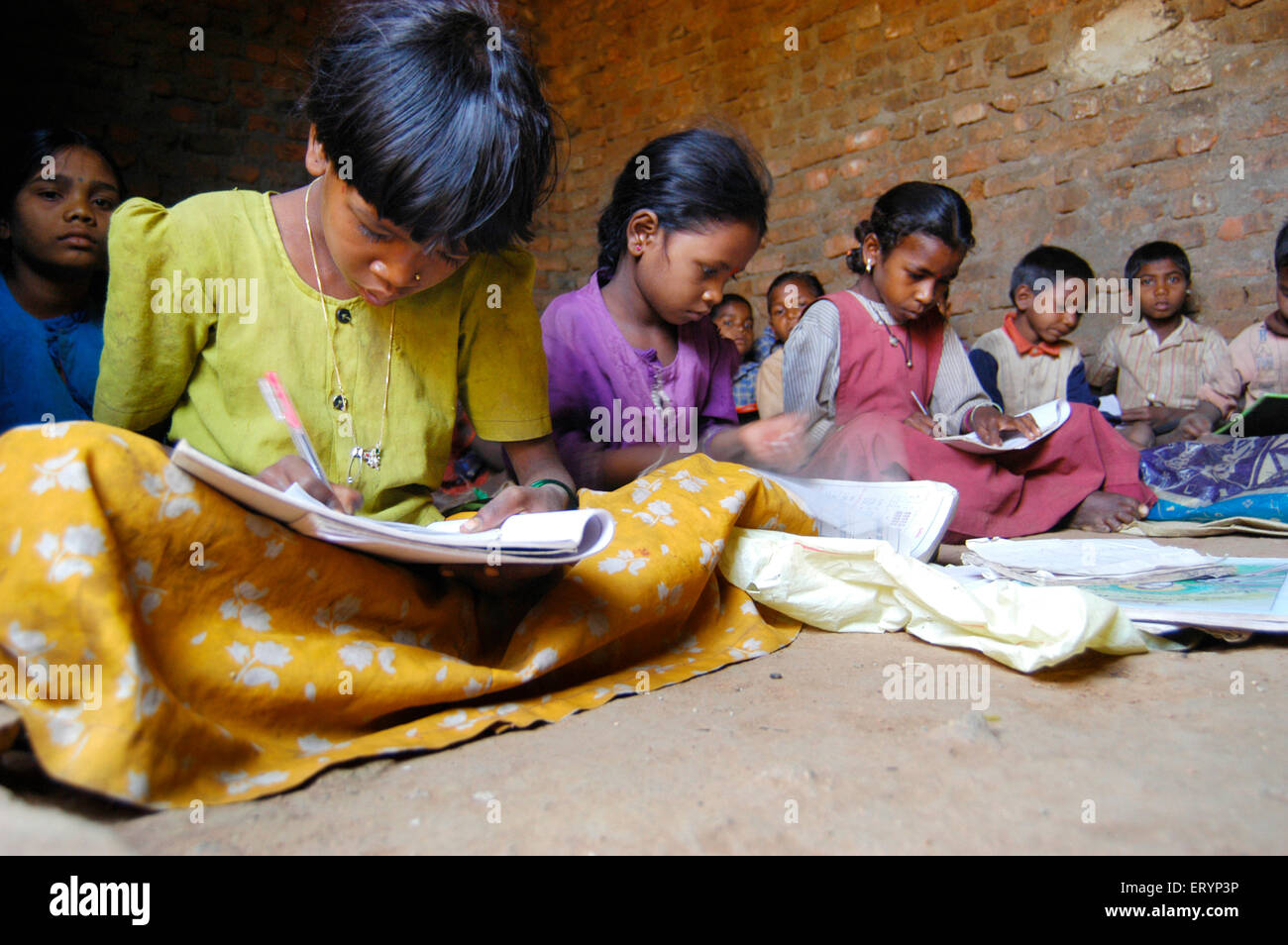 Bambini tribali ragazze e ragazzi che imparano a scuola gestito da ONG Organizzazione non governativa nel villaggio seduto al piano India Asia Foto Stock
