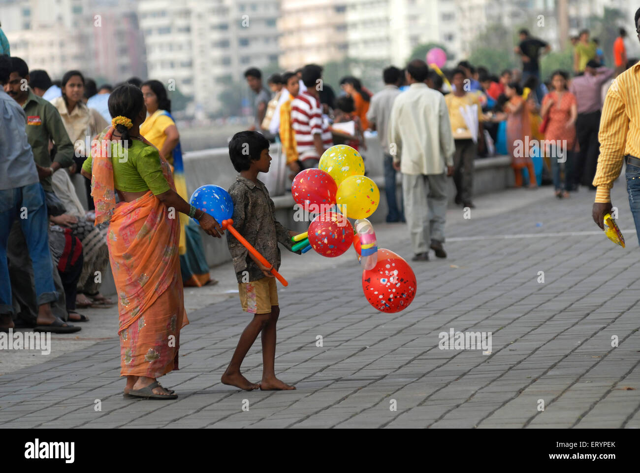 Ragazzo giovane insieme con sua madre vende palloncini colorati per i turisti in visita a Marine Drive a Bombay Mumbai Foto Stock