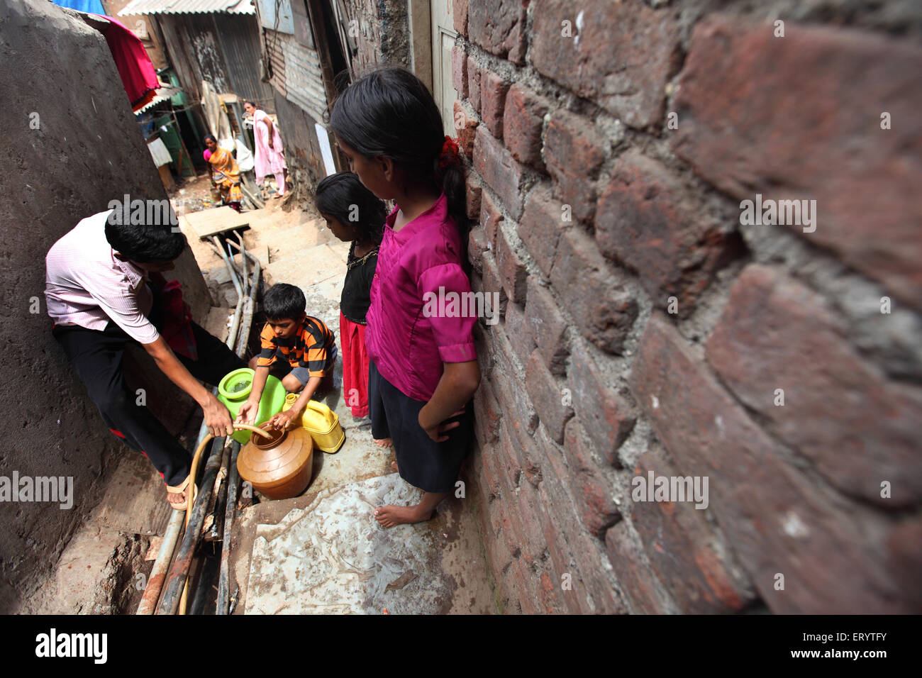 Mancanza di acqua , gente di baraccopoli che riempie il vaso di acqua dal tubo , Bombay , Mumbai ; Maharashtra ; India , Asia Foto Stock