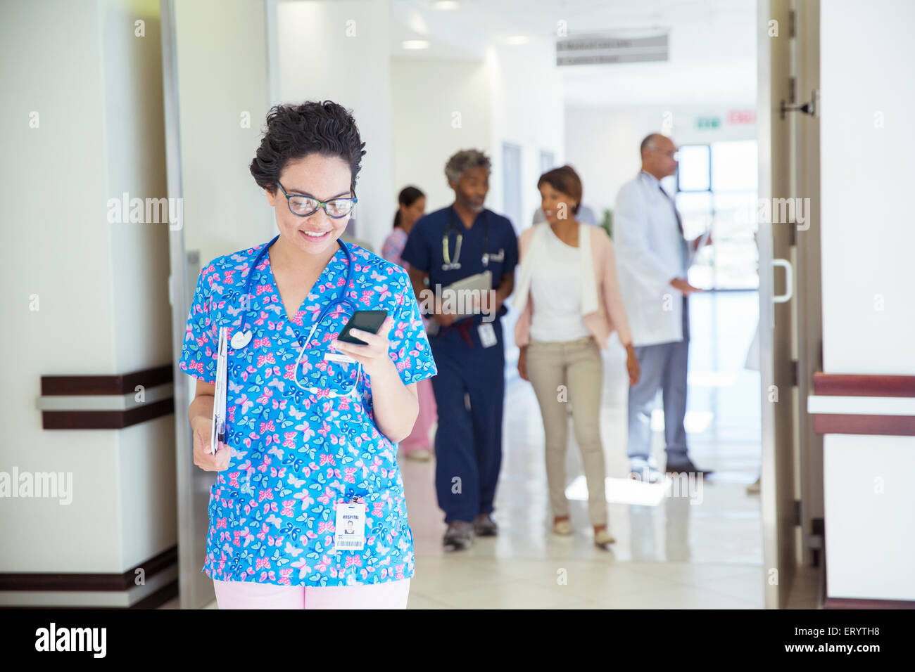 Un infermiere gli sms sul cellulare in ospedale corridoio Foto Stock
