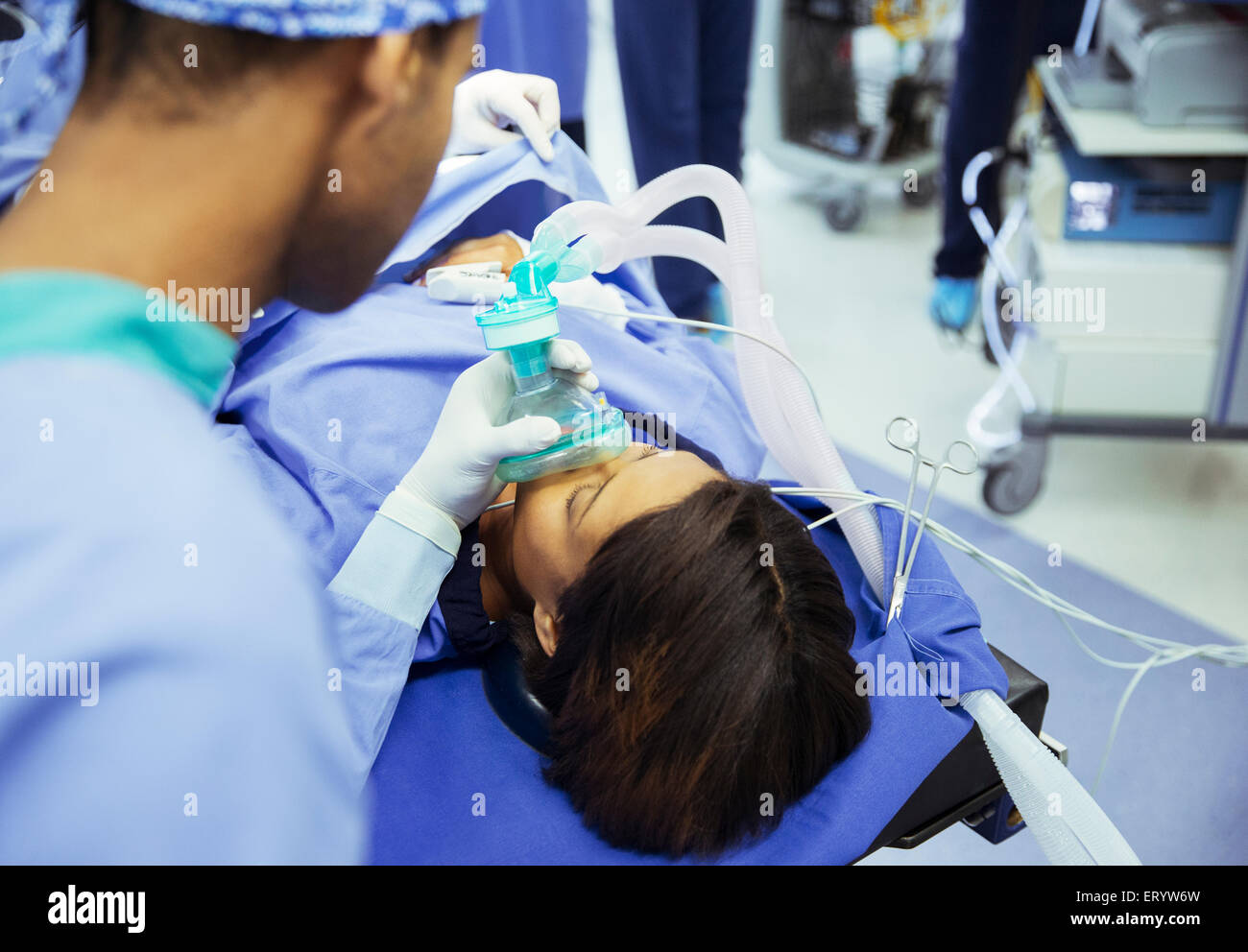 Anestesista tenendo le maschere di ossigeno oltre il viso del paziente in sala operatoria Foto Stock