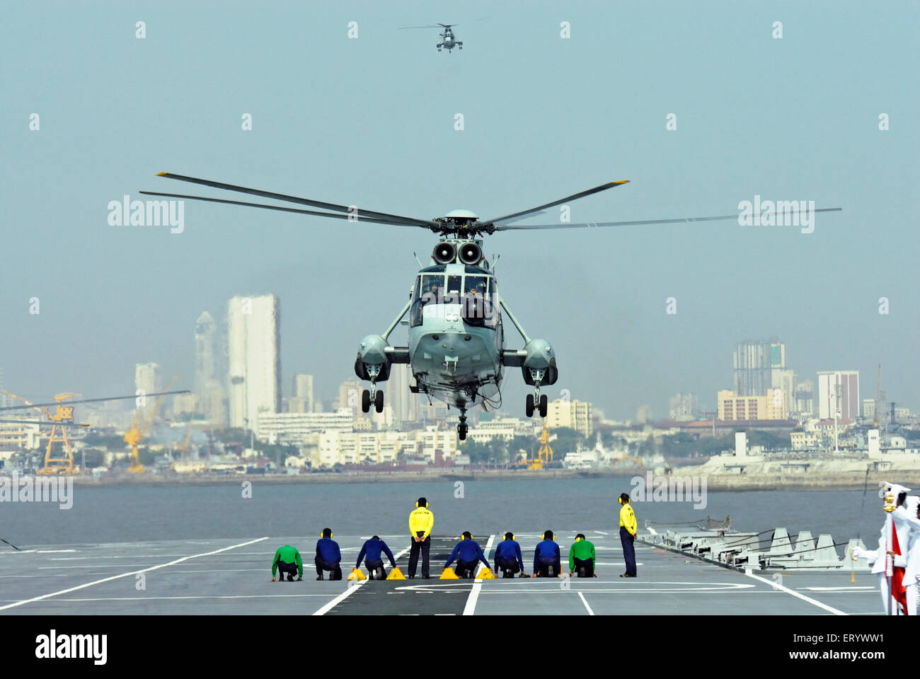 Controllore di pista della Marina indiana guida mi 18 di atterraggio per elicotteri sul ponte della portaerei INS viraat R22 Mumbai Foto Stock