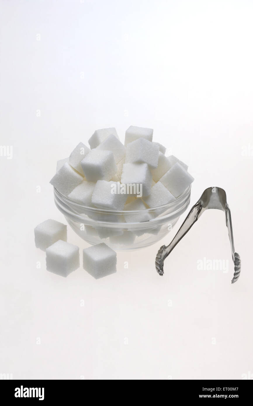 Zollette di zucchero in un recipiente di vetro con le pinze Foto Stock