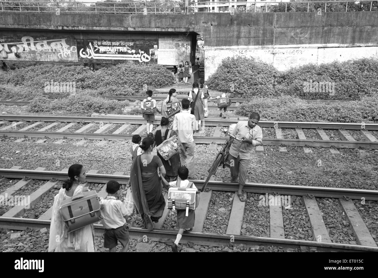 Le donne con bambini di attraversamento della linea ferroviaria in baraccopoli Islampura ; Wadala ; Mumbai Bombay ; Maharashtra ; India Foto Stock