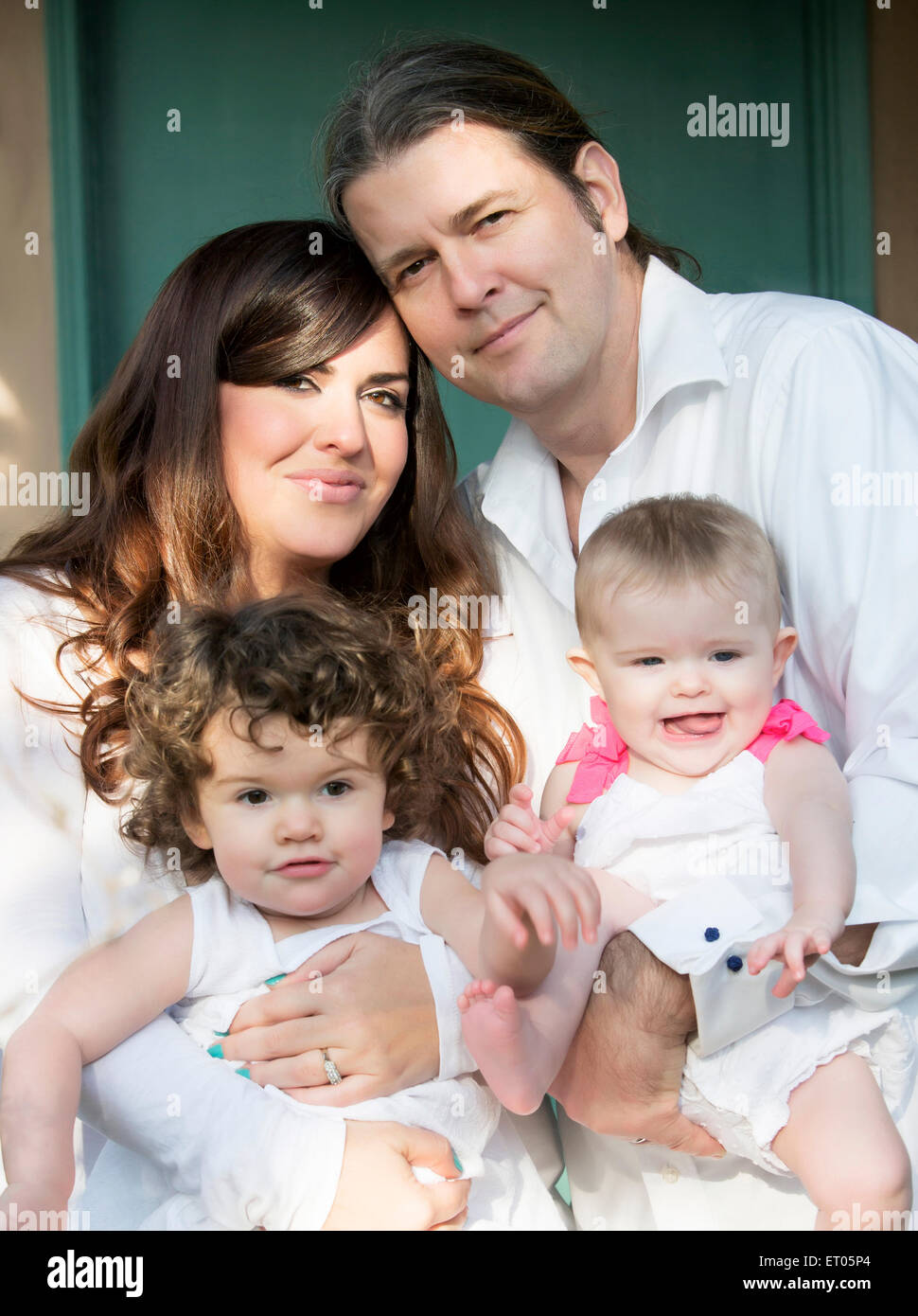Ritratto di giovane famiglia con due bambini vestiti di bianco Foto Stock