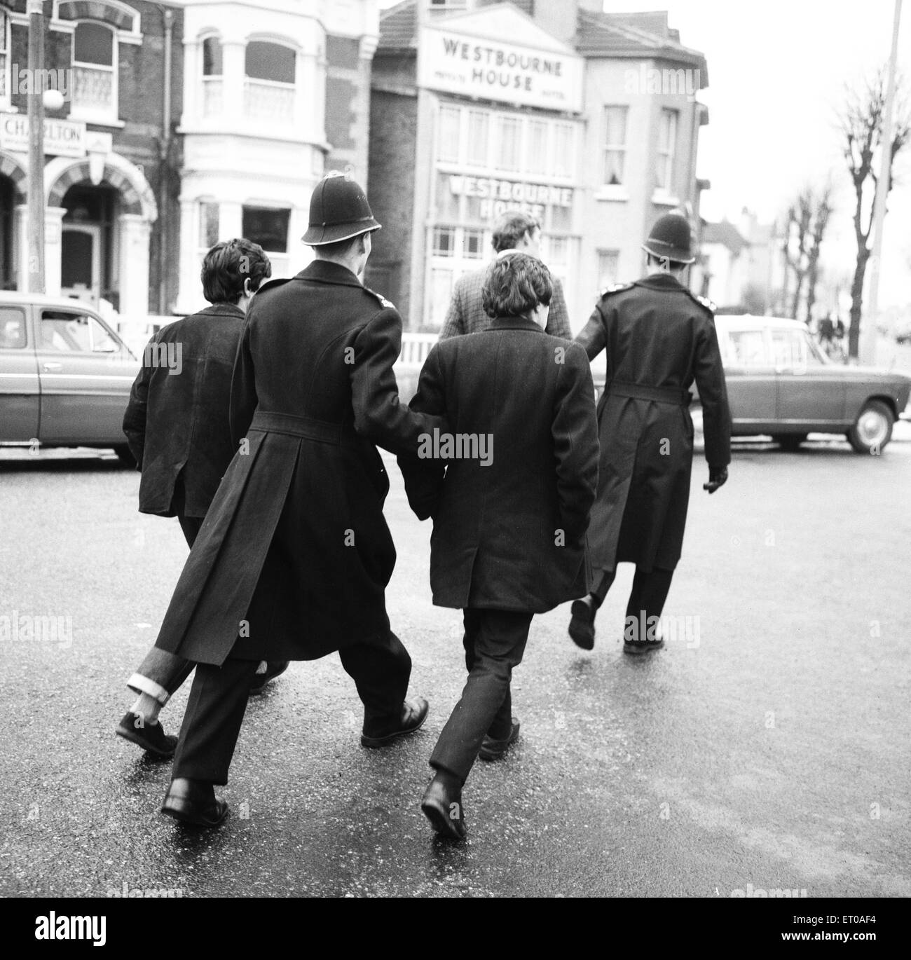 Due poliziotti scortare i prigionieri alla stazione di polizia locale a seguito di un incidente sul Clacton fronte mare. Oltre il 1964 il week end di Pasqua diversi tafferugli tra mods e Rockers scoppiò in Essex cittadina sul mare. Il 30 marzo 1964 Foto Stock