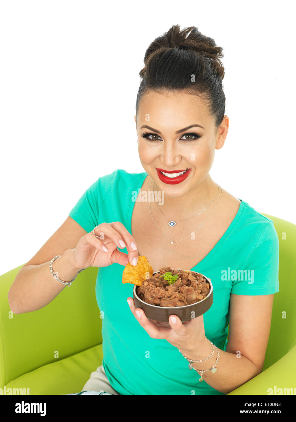 Fiducioso positivo felice giovane donna ispanica mangiare autentico stile messicano refried fagioli piccanti con Nachos isolata contro uno sfondo bianco Foto Stock