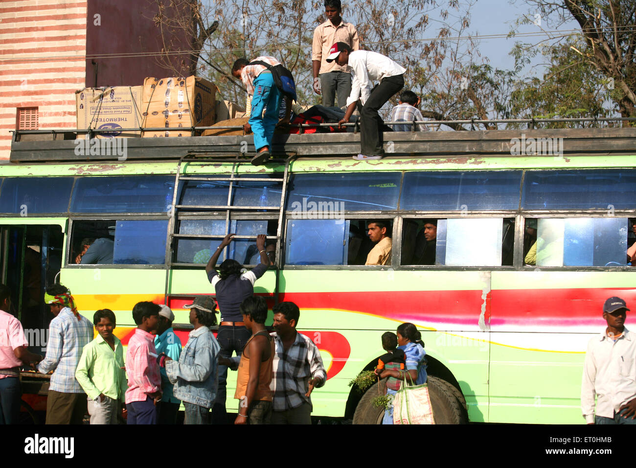 Passeggeri Indian uomini e donne salendo sulla sommità di autobus del trasporto locale per l inter città di destinazione del trasporto in Jharkhand India Foto Stock