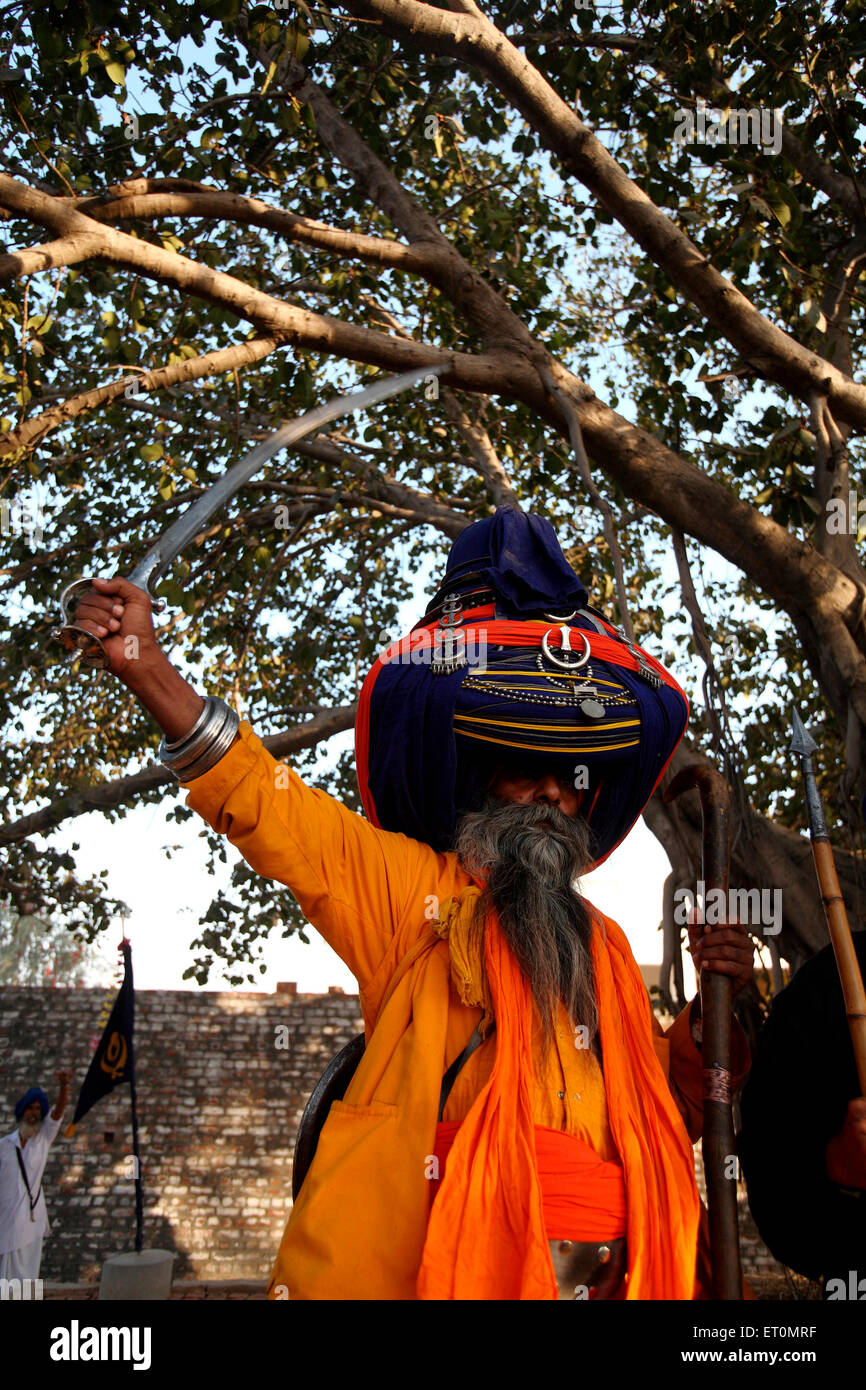 Nihang o guerriero Sikh in pagdi o cappelli che porta la spada e bastone di legno durante le celebrazioni della Hola Mohalla Foto Stock