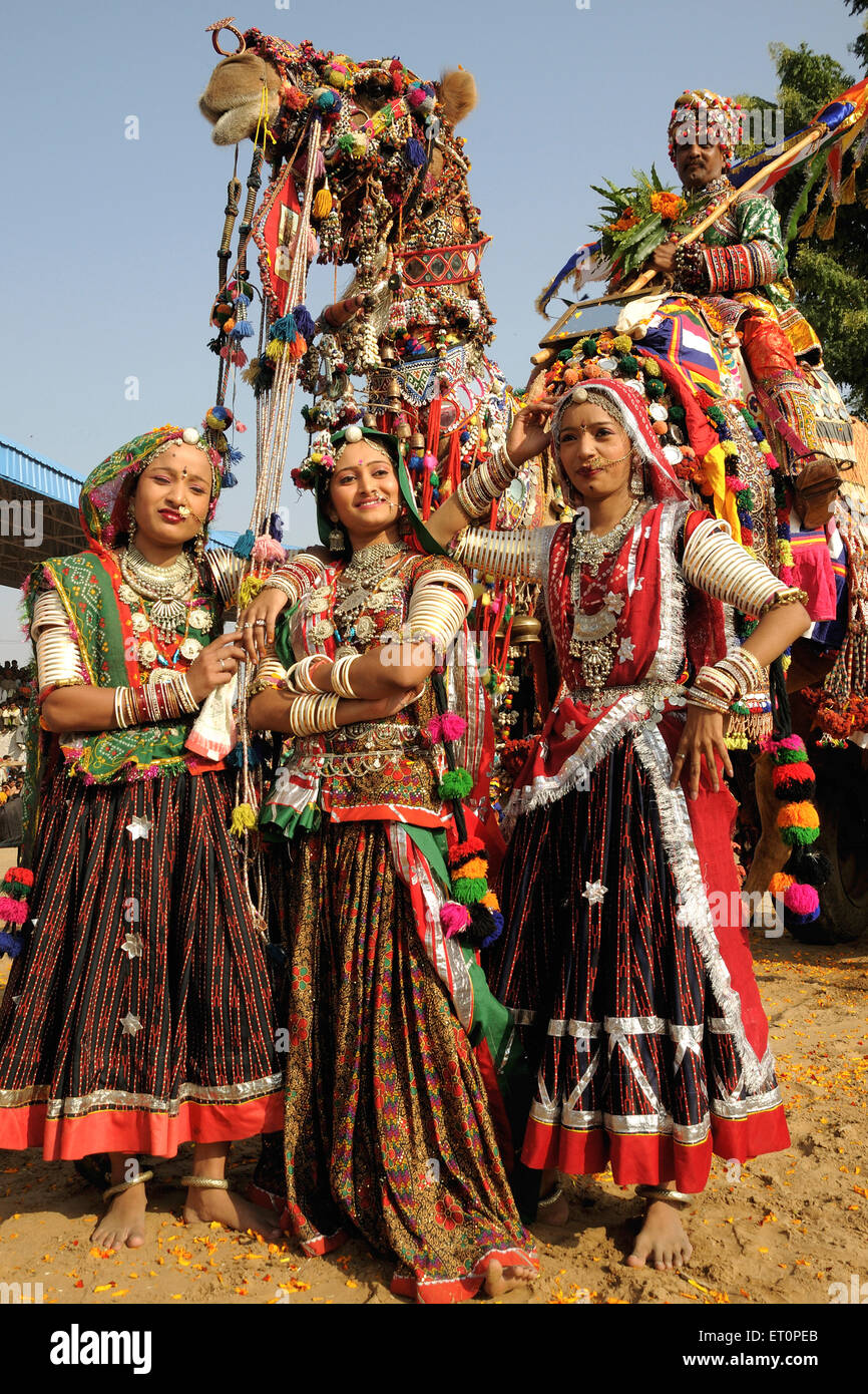 Ragazze in gioielli tradizionali e di costume di Rajasthani in piedi nella parte anteriore del cammello decorate in Pushkar fair ; Rajasthan Foto Stock