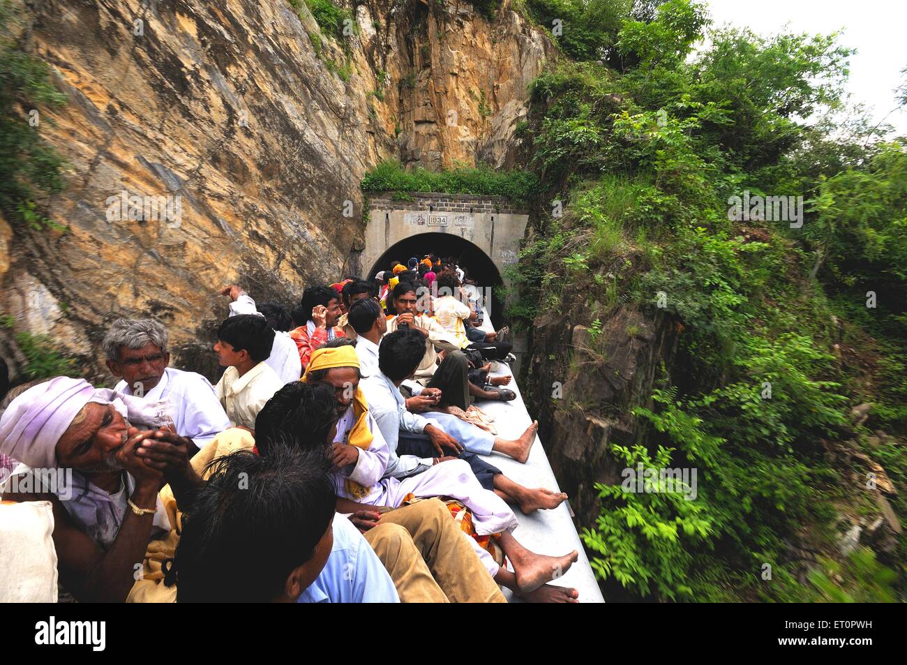 Le persone che assumono il rischio durante il viaggio sul tetto del treno diretto attraverso il tunnel ; Rajasthan ; India Foto Stock