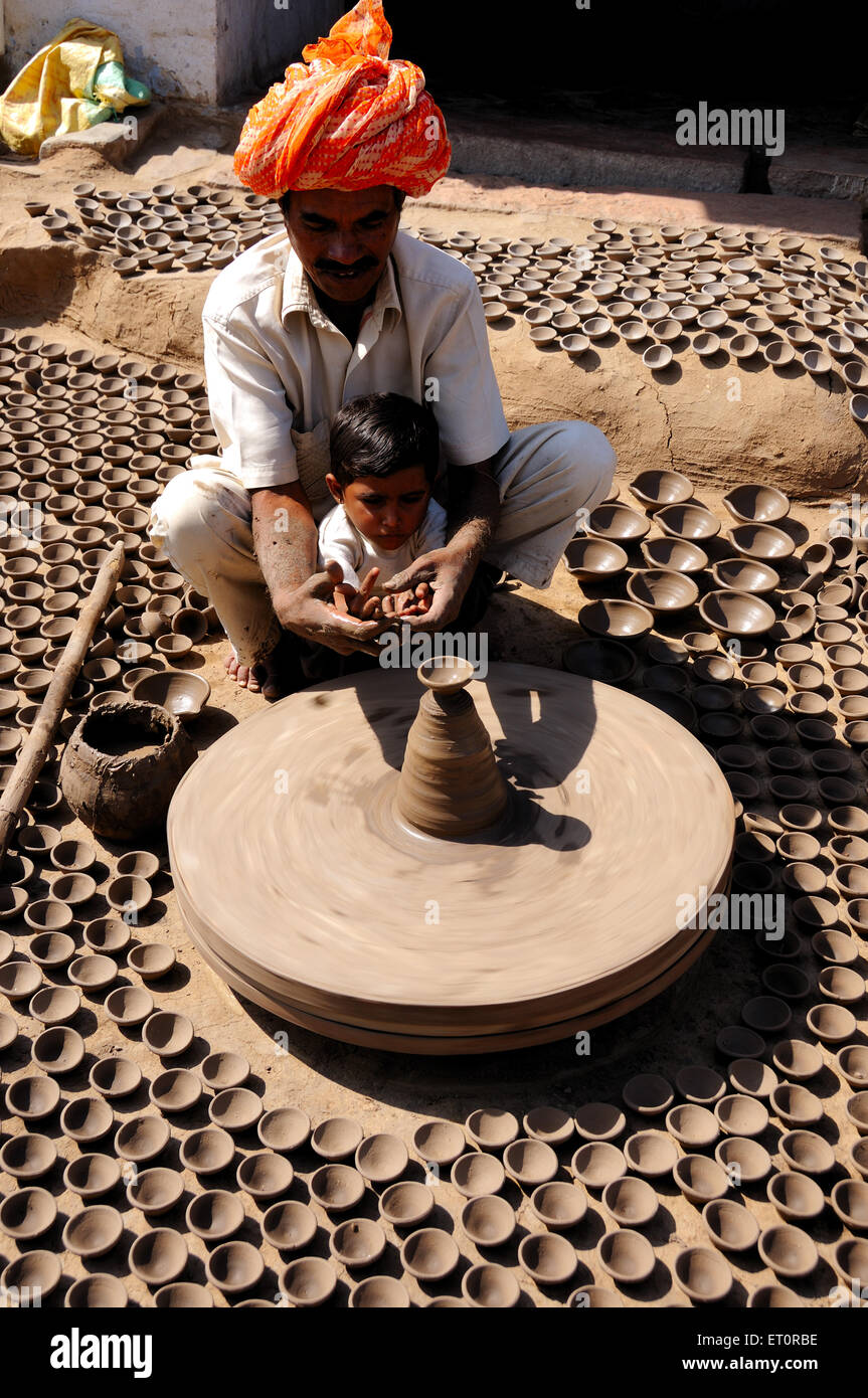 Potter con suo figlio rendendo le lampade di sabbia su una ruota potter ; Jodhpur ; Rajasthan ; India Signor#786 Foto Stock