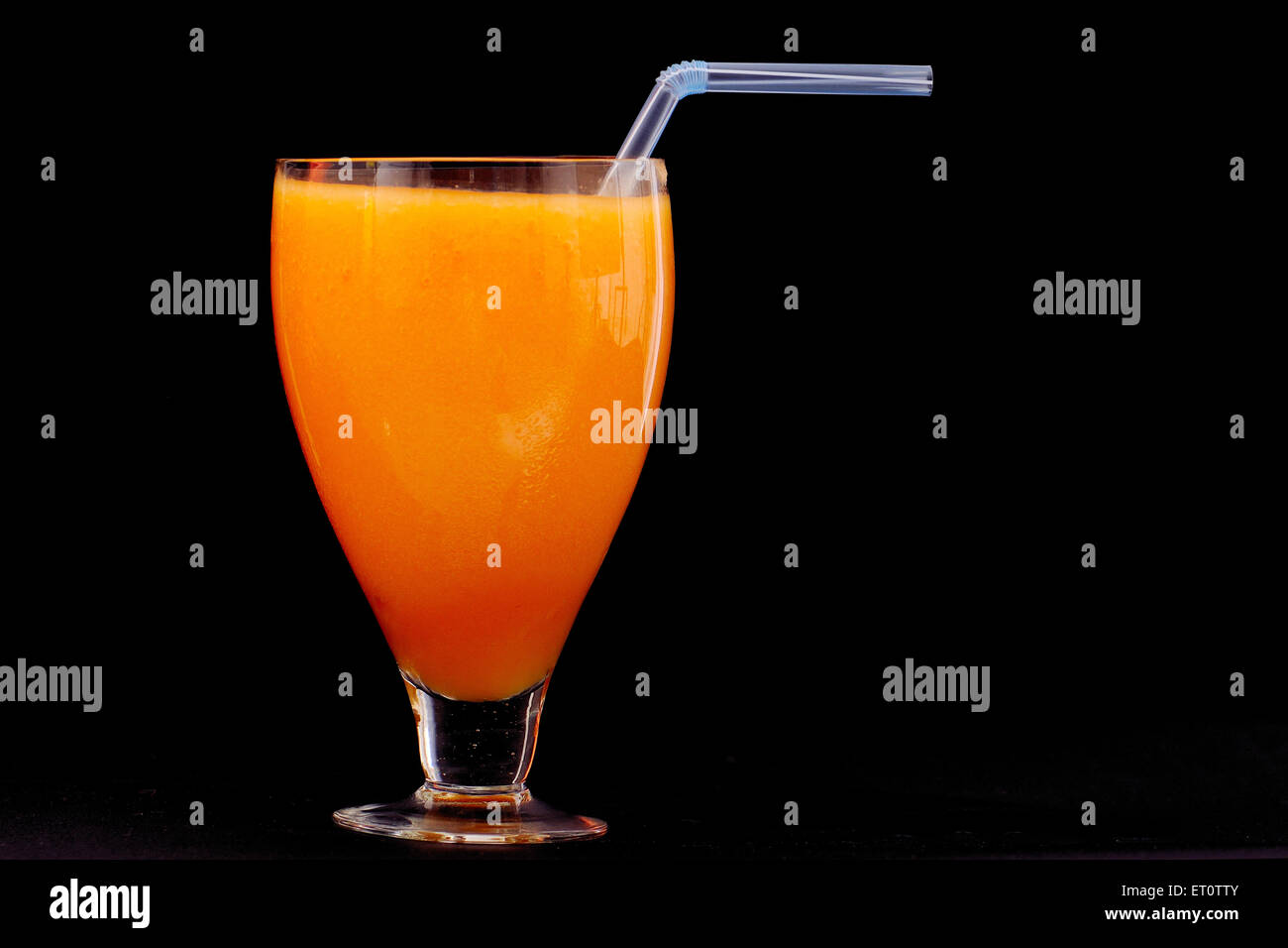 Succo d'arancia in vetro con cannuccia su fondo nero Foto Stock