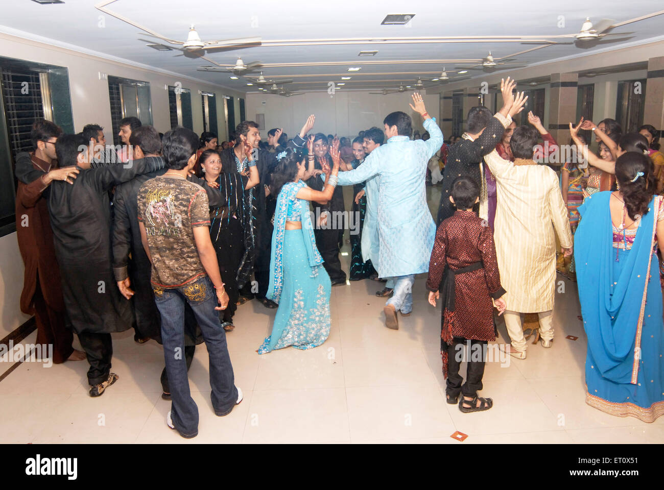 Gujarati familiari dancing in hall di notte ; per festeggiare un giorno prima del matrimonio ; Mumbai Bombay ; Maharashtra ; India Foto Stock