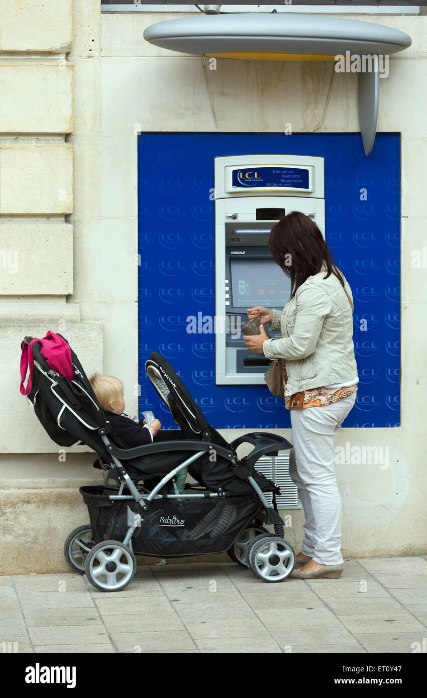 Reims, Francia, Donna con bambino presso un Bancomat della Banque et Assurance LCL Foto Stock