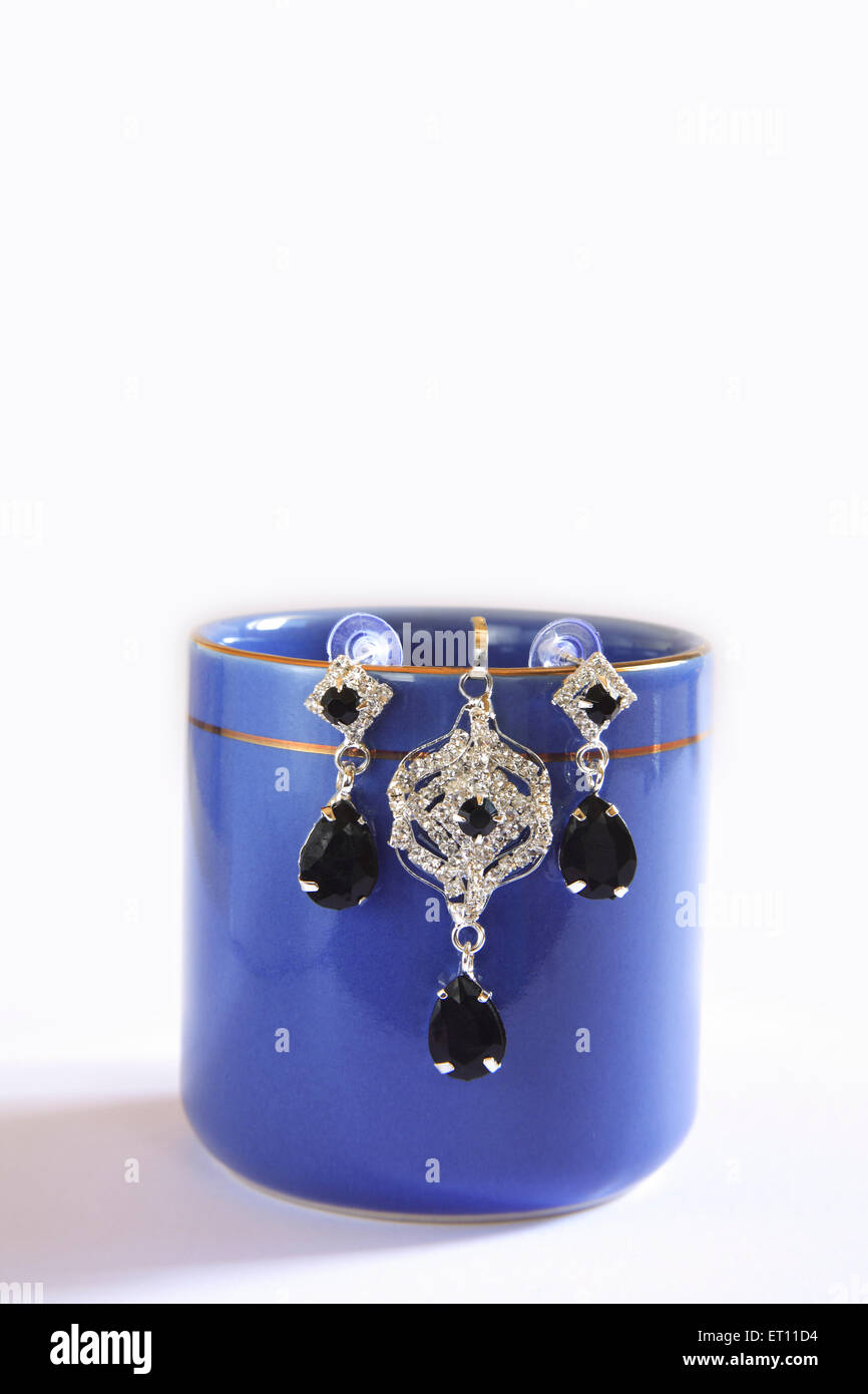 Orecchini appendere su blu tazza da caffè su sfondo bianco Foto Stock