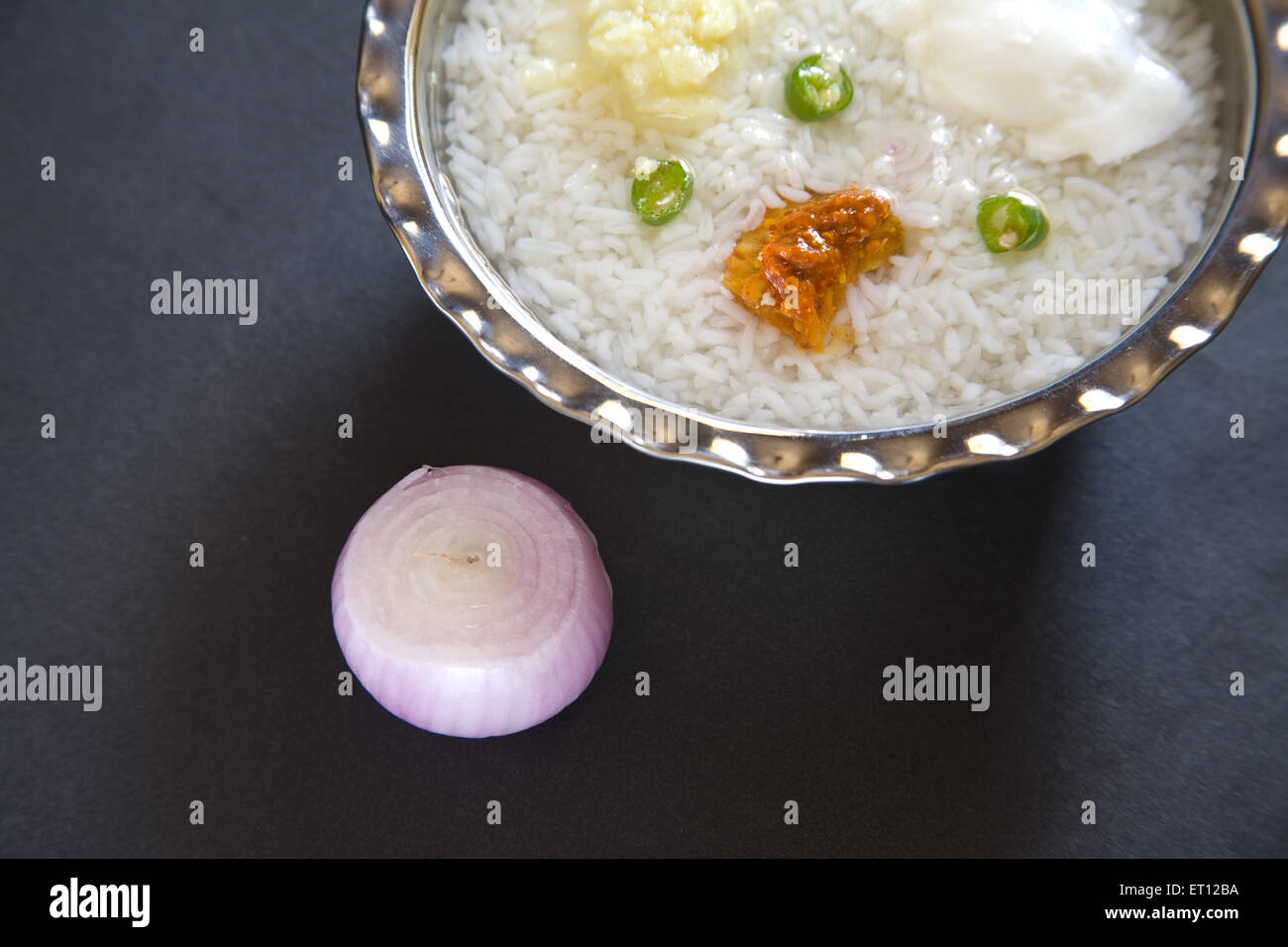 Pranzo indiano pakhala riso pickle schiacciare le patate con peperoncino e yogurt in acciaio ciotola cipolla sfondo nero Foto Stock