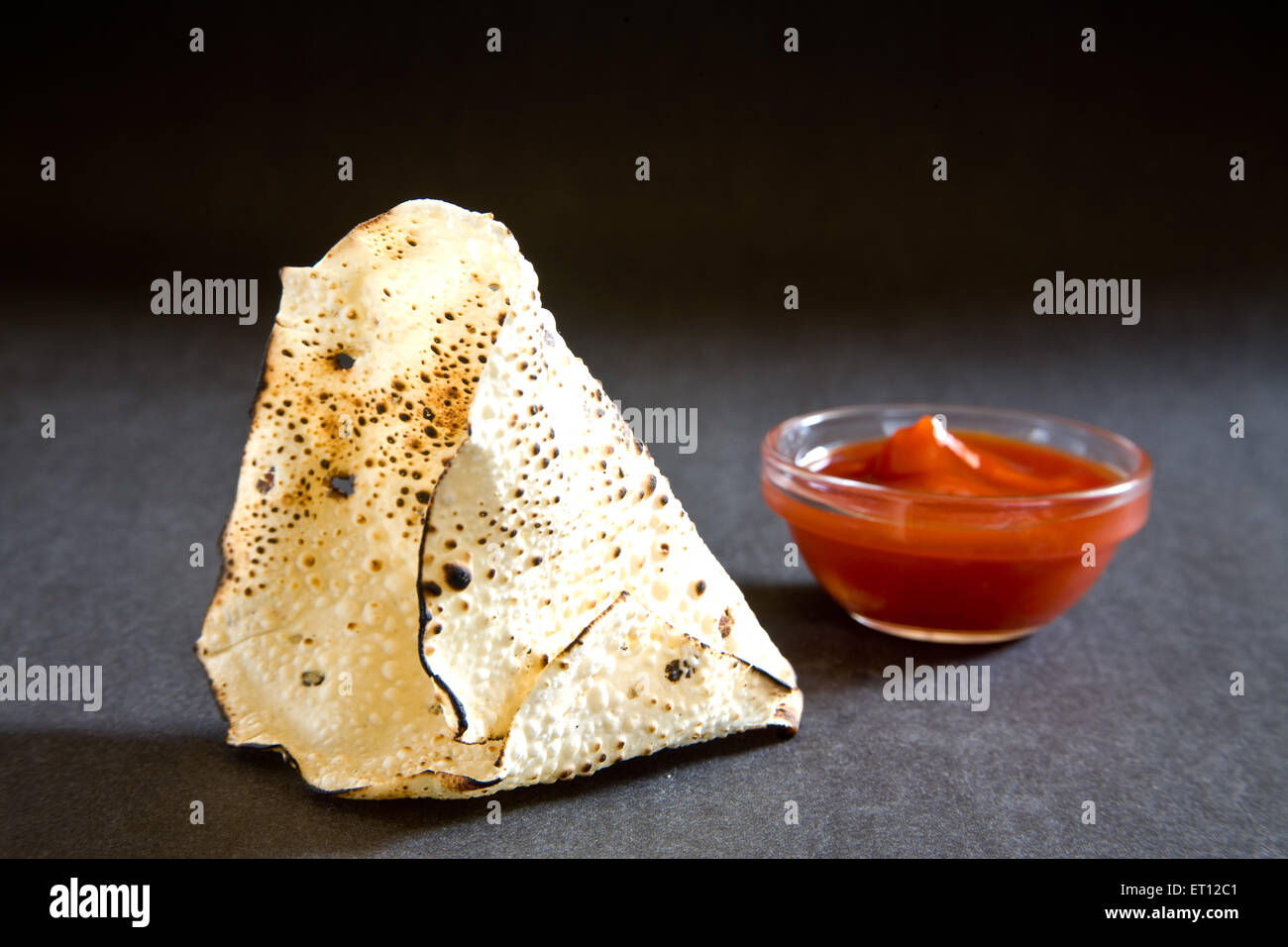 papad arrosto, papadum, papadom, snack indiano, cracker, ketchup di pomodoro, forma conica, fondo nero Foto Stock