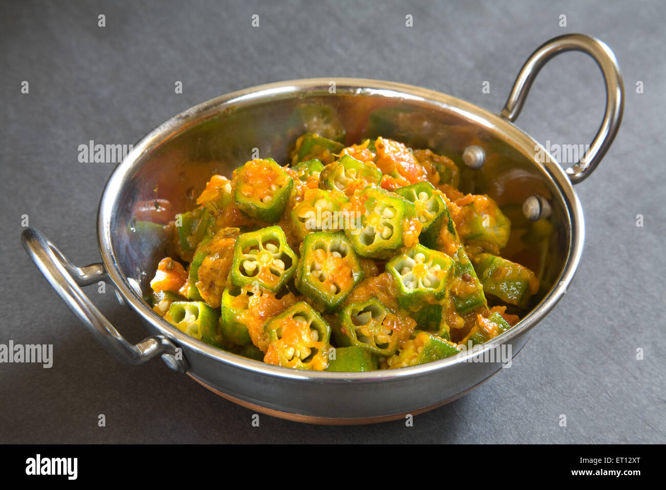 Cucina indiano Masala lady dito okra Hibiscus Esculentus in acciaio kadahi su sfondo nero Foto Stock