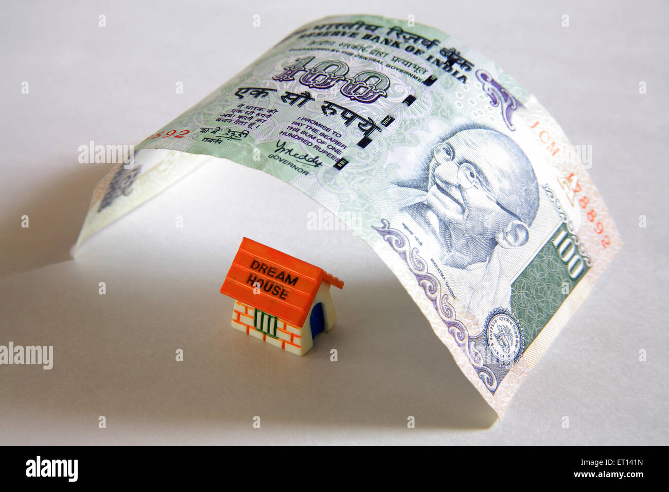 Prestito di alloggiamento, modello domestico di plastica sotto cento nota di rupie su sfondo bianco Foto Stock