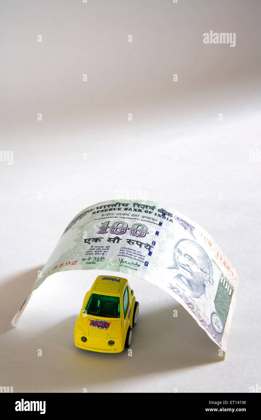 Concetto di prestito dell'automobile, modello giallo dell'automobile della plastica sotto cento rupie su sfondo bianco Foto Stock