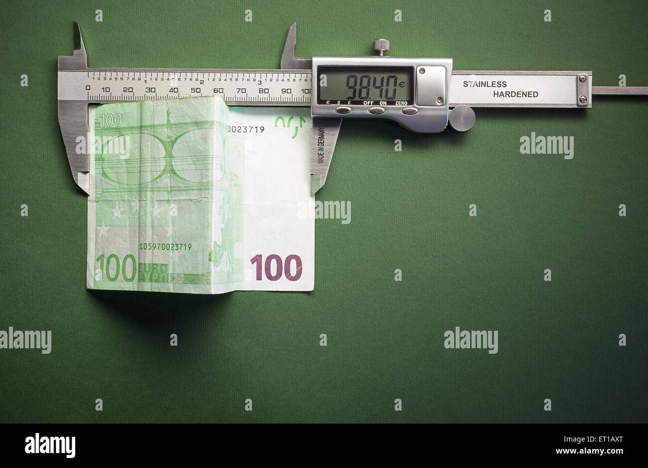 Composizione concettuale che rappresentano fondi svalutazione, simbolicamente mostrato con pinza scorrevole la misurazione di un centinaio di euro. Foto Stock