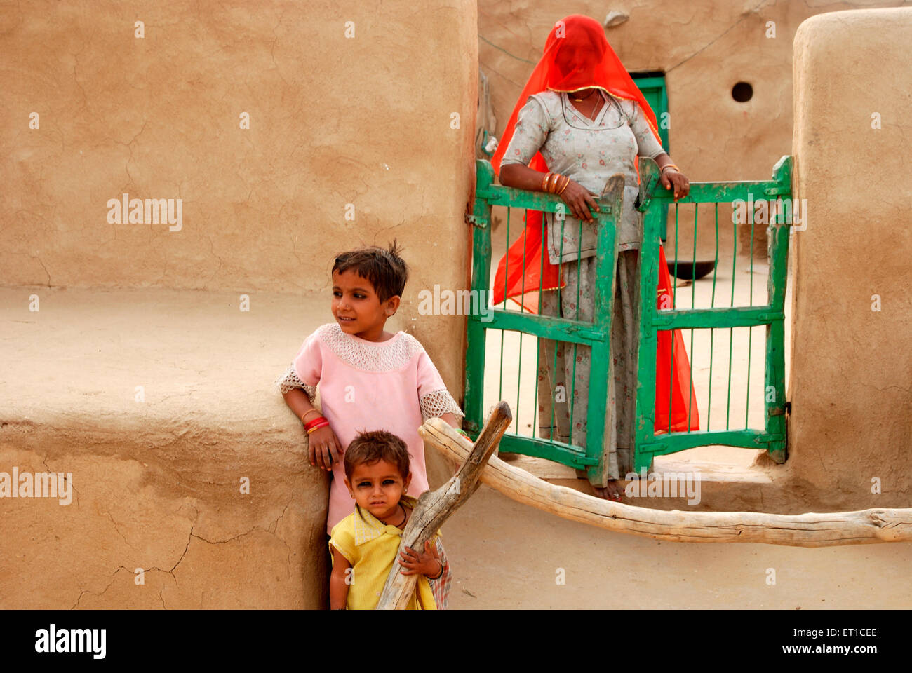 Rajasthani donna con i bambini nella capanna di gobar o bestiame bovino sterco cercando curiosamente Khuhri ; ; ; Jaisalmer Rajasthan ; India n. MR Foto Stock