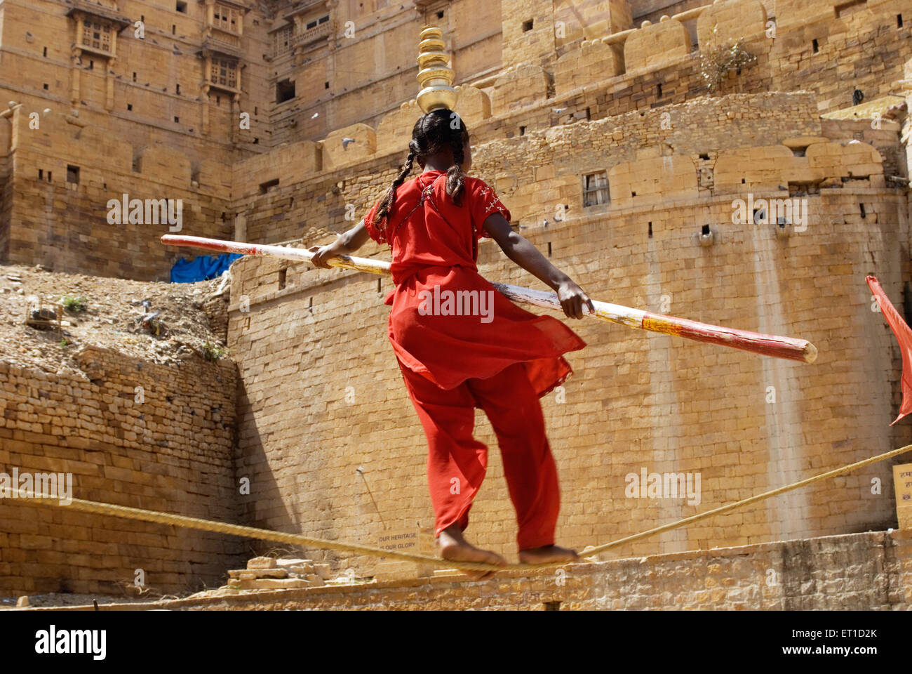 Ragazza con bambù in mani di eseguire acrobat sulla corda ; Jaisalmer ; Rajasthan ; India Foto Stock