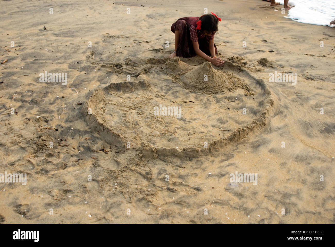 Ragazza rendendo casa di sabbia sulla sabbia a cherai beach ; Cochin ; Kerala ; India Foto Stock