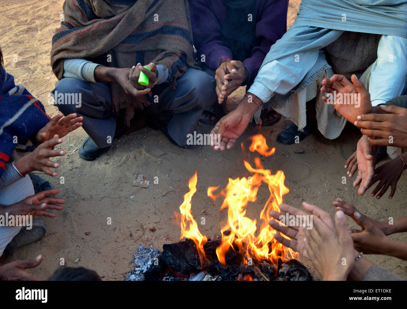 Gli abitanti di un villaggio di riscaldamento seduti intorno al fuoco Bikaner Rajasthan India Asia Foto Stock