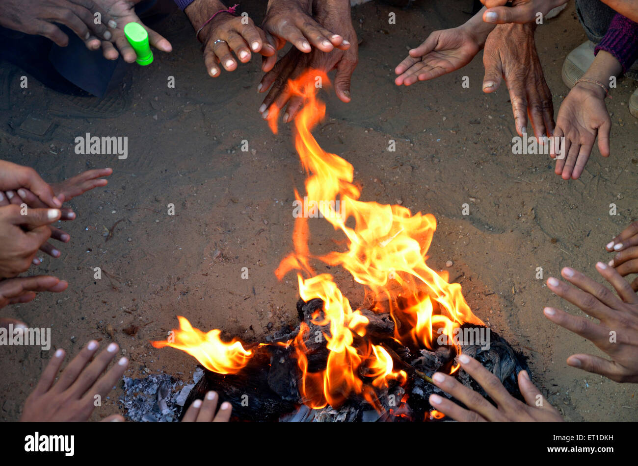 Popolazione rurale indiana abitanti del villaggio che si riscaldano seduti intorno al fuoco in inverno freddo ; Bikaner ; Rajasthan ; India ; Asia Foto Stock