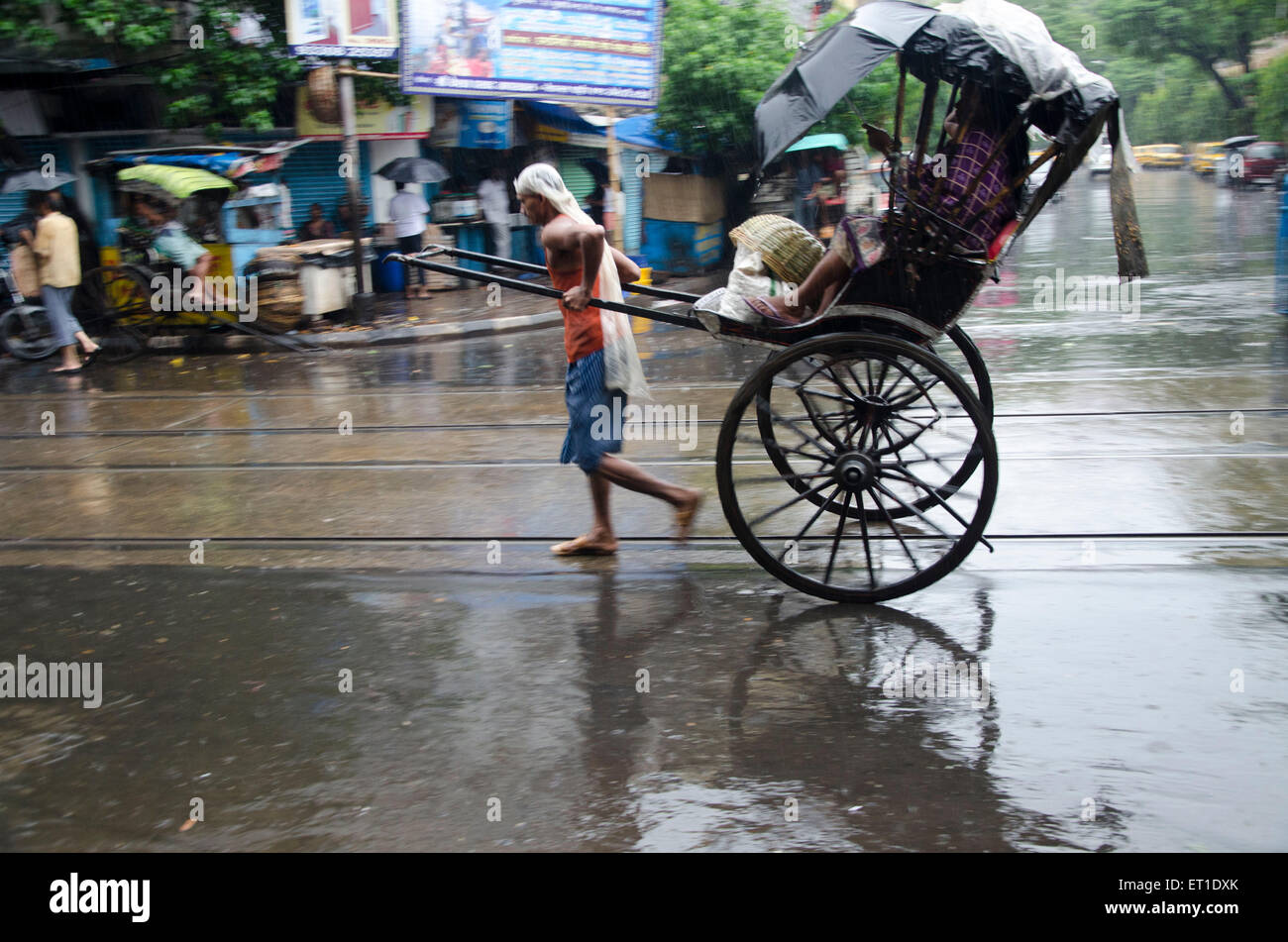 Man mano tirando il rickshaw con passeggero su street Kolkata West Bengal India Asia Foto Stock