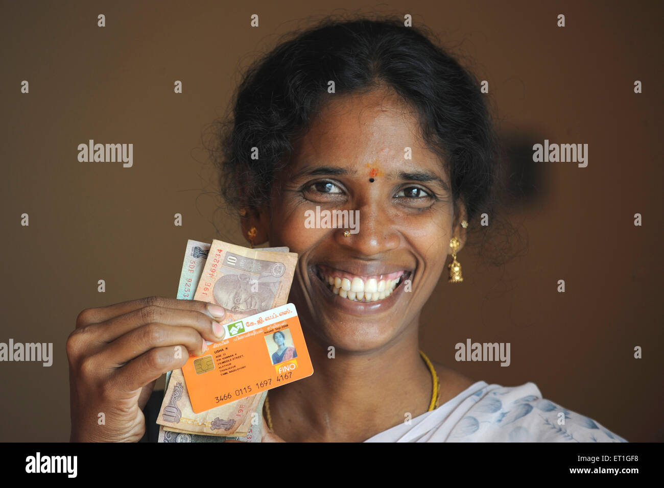 Signora rurale che mostra in contanti e con carta di identità della banca dalle ONG Gramin Kshtriya Servizi Finanziari IFMR Foundation, Thanjavur, India Foto Stock