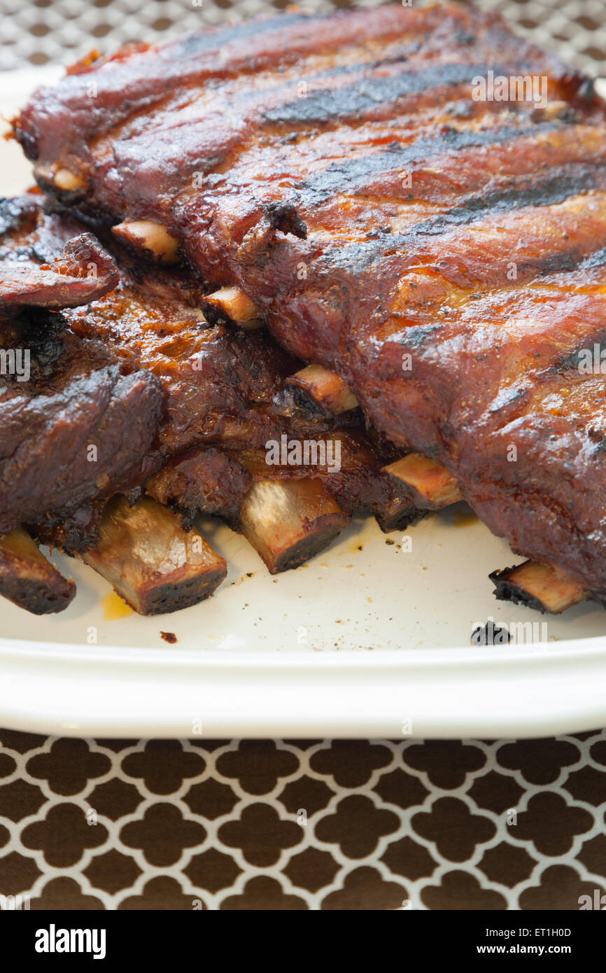 Costolette di maiale sedersi sulla cima di una piastra bianca dopo essere stata disseccata sulla griglia e quindi lenta tostate in forno. Foto Stock
