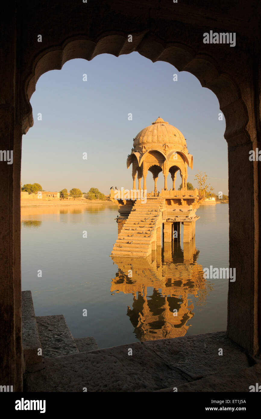 Cenotafio chiamato chhatri riflessione in acqua attraverso arco in Gadsisar o lago Gaddisar ; Jaisalmer ; Rajasthan ; India ; Asia Foto Stock