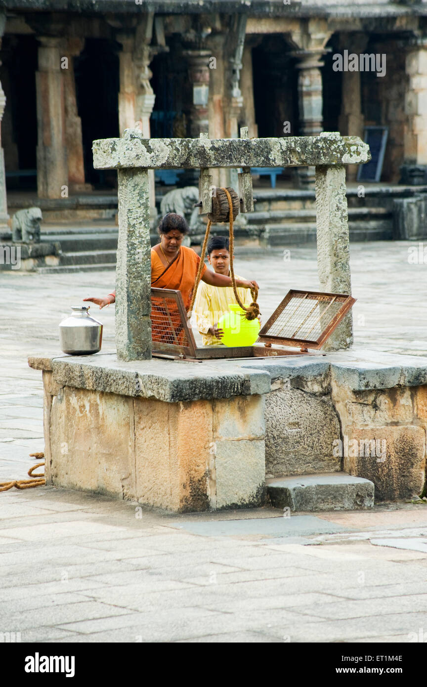 Sud donna indiana con ragazzo il prelievo di acqua dal bene ; Karnataka ; India NOMR Foto Stock