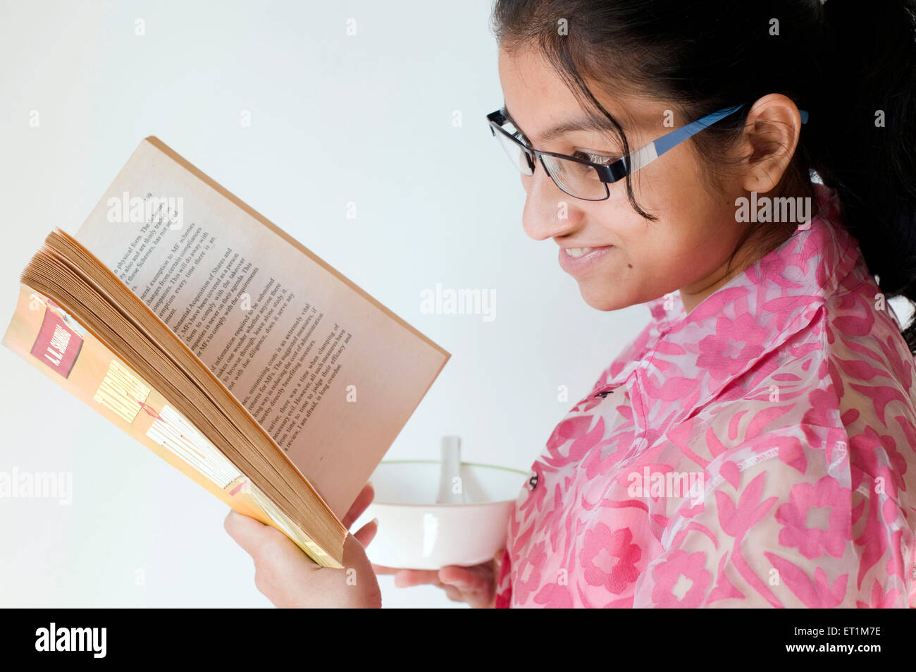 Una ragazza con un recipiente vuoto e la lettura del libro di Pune India Maharashtra Asia signor#686EE Foto Stock