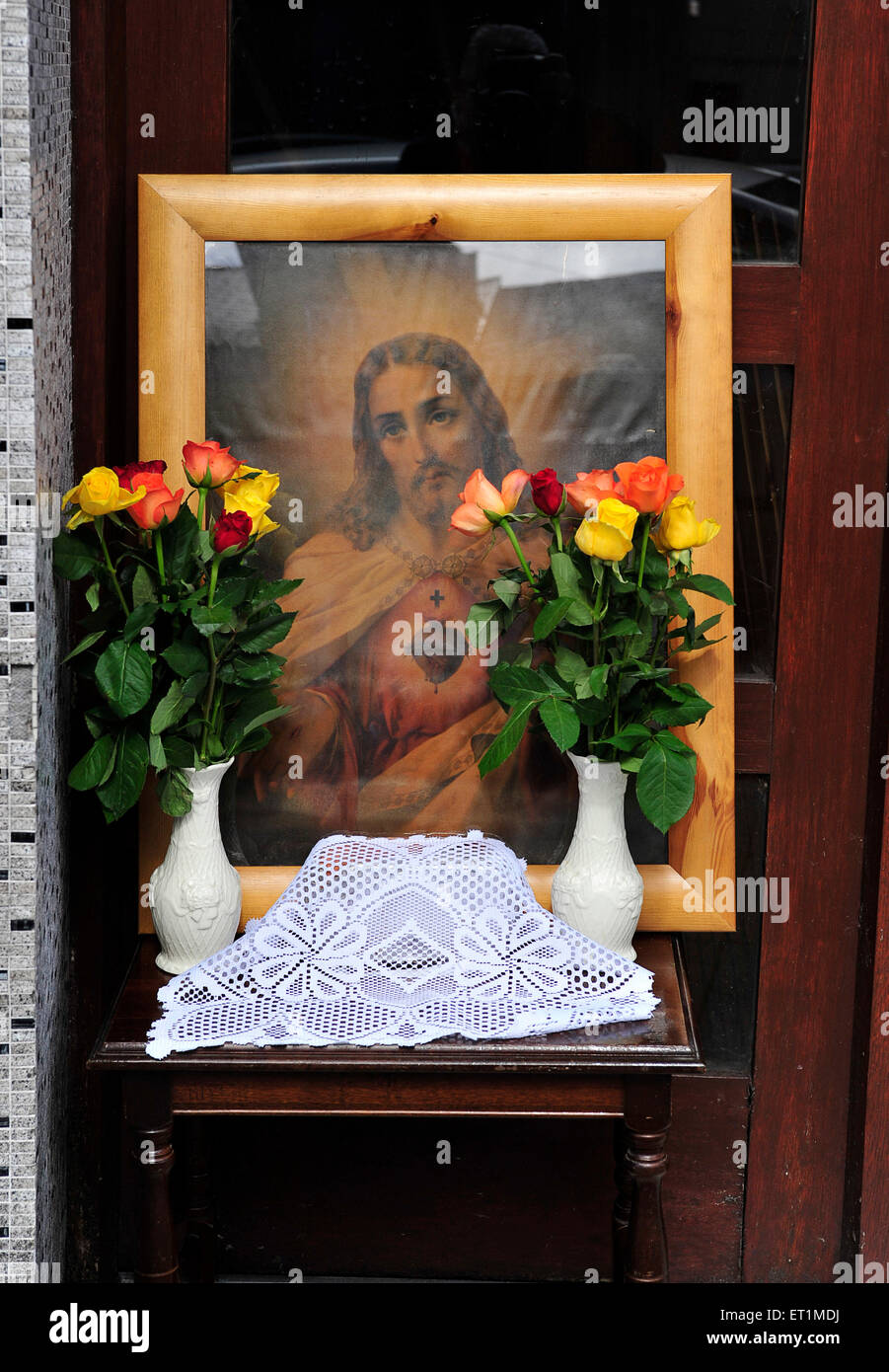 Immagine inquadrata di Gesù circondato da fiori al di fuori di una casa in Buncrana, County Donegal, Irlanda in occasione della festa del Corpus Domini. Foto Stock