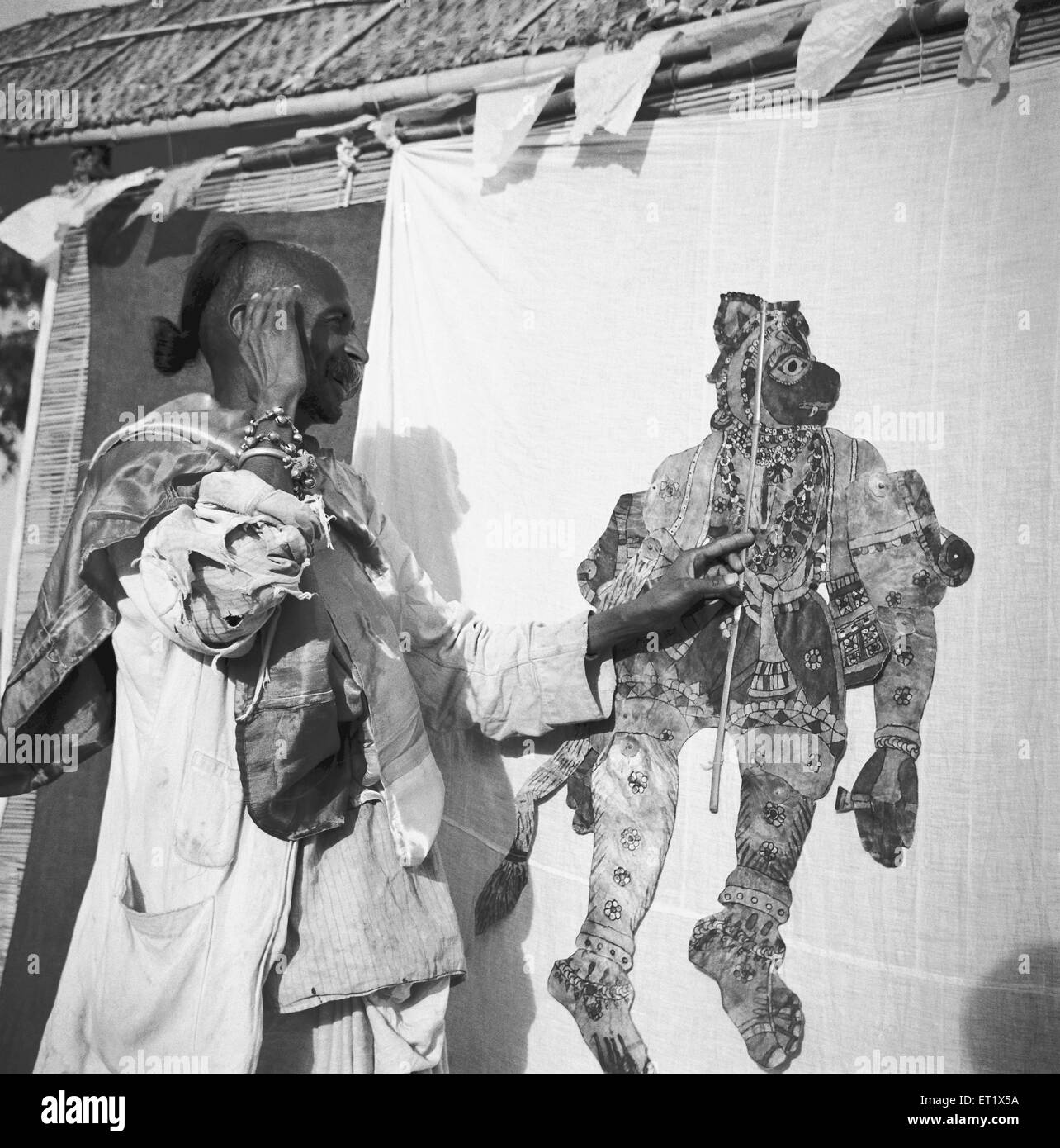 Gli uomini in piedi dietro il telo schermo luce gettato manipolare cuoio fantoccio piatto shadow puppet giocare ; Hallare village ; Mysore Foto Stock