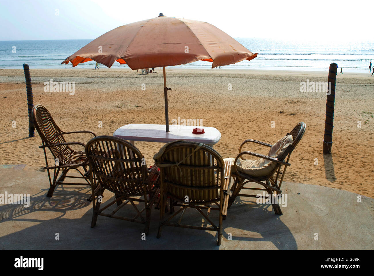 Sedie di canna e tavolo di plastica sotto ombrello, spiaggia di Candolim, Panjim, Panaji, Goa, India, Asia Foto Stock