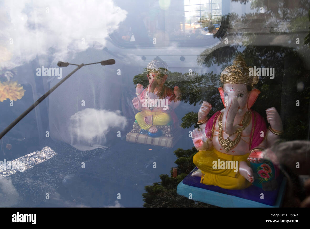 Gli idoli del signore ganesha ganpati e di riflessione nella protezione contro il vento del veicolo in auto ; Pune ; Maharashtra ; India Foto Stock