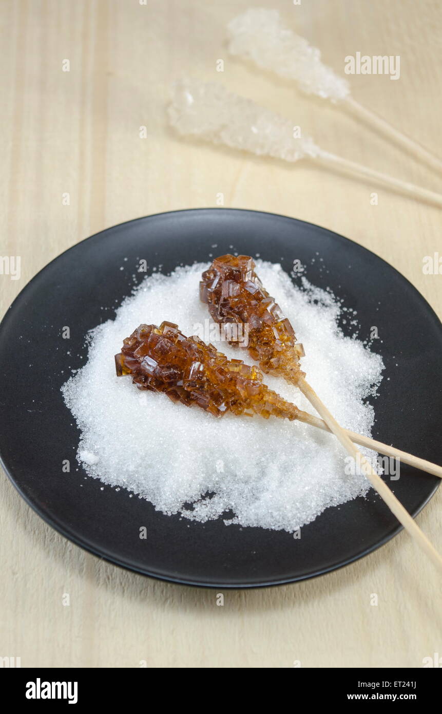 Due bastoncini di zucchero contenenti bianco e zucchero di canna in una piastra nera Foto Stock