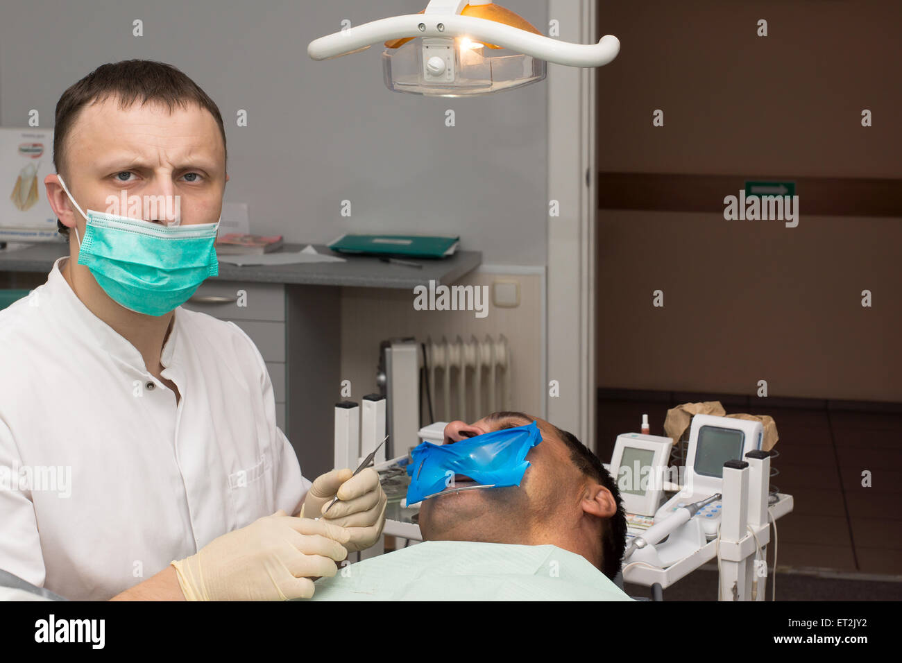 Dottore in bianco abito medico considera denti paziente Foto Stock